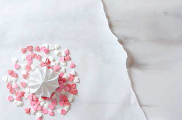 Meringue and heart sprinkles on the baking paper on the marble table.Concept of greeting card template, top view