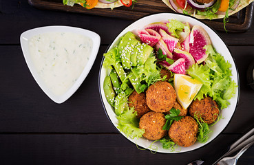 Falafel and fresh vegetables. Buddha bowl. Middle eastern or arabic dishes on a dark background. Halal food. Top view. Copy space