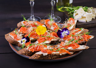 Salmon sandwiches with cream cheese and microgreen on wooden table. Canape with salmon.