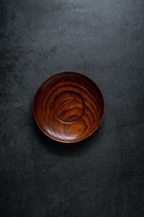 An empty wooden dish on a black background