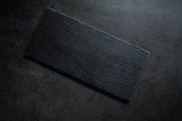 An empty black slate plate on a black background