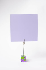 Note sheet inscriptions. Pink, blue, filet paper on a clothespin holder on white background, text space. Place for inscription.