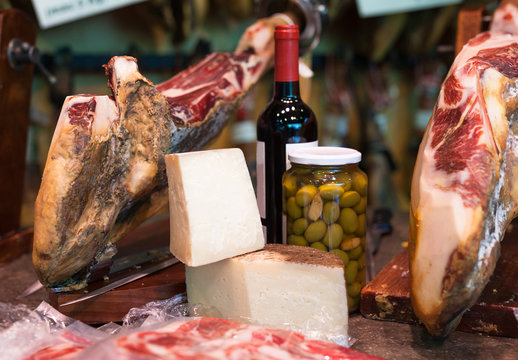 Still life of spanish pork jammon on holder, bottles of wine cheese and olives