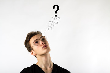 Young man is full of doubts and hesitation. Young man and Question marks.