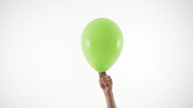 Two hands burst green balloon with needle