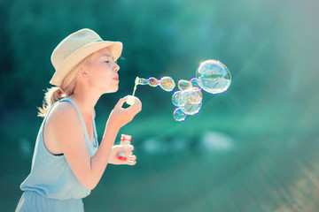Teenage girl blowing soap bubbles outdoors