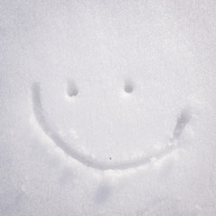 Happy face smiley drawn on white snow, frosty winter day.