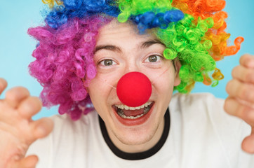 Naklejka premium young funny male teenager in white t-shirt on blue background in clown wig close-up portrairt
