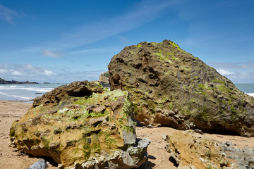 Big green stones on a sandy beach. Beautiful landscape on the ocean. Atlantic coast in southwestern France