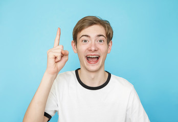 young funny male teenager in white t-shirt on blue background has idea