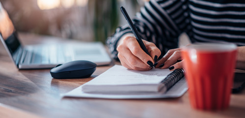Woman writing notes in notebook