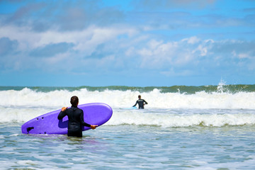 Surfing school. Boy with a surfboard in his hands. Surfer wants to catch ocean wave