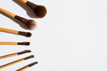 Top view of make up brushes set, arranged in a beautiful line. Natural accessories with bamboo wood handles. Copy space in the middle.