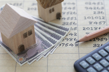 お札と家の模型と数字と電卓と鉛筆