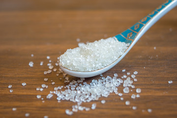 Close up of sugar in spoon on a wooden table. Copy space provided