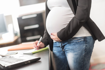 Pregnant woman taking notes at office