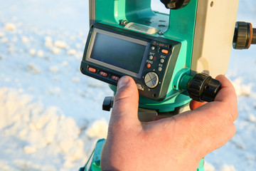 surveyor's finger presses the button on the total station. geodetic equipment is ready to work. the surveyor takes measurements. the hand of the surveyor sets up equipment for operation.