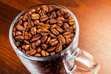 Roasted coffee beans in a glass cup isolated on a rustic dark wood table background