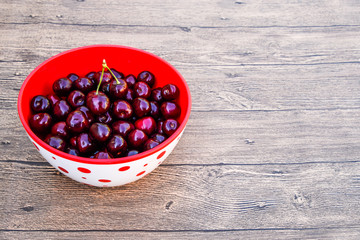 Berries of a sweet cherry on a wooden background in a plastic cup. Ripe red sweet cherry