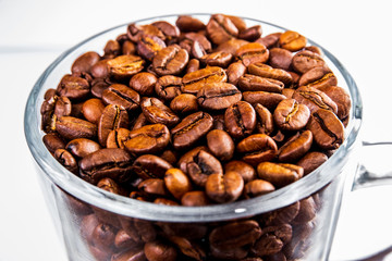 Roasted coffee beans in a glass cup isolated on a white background