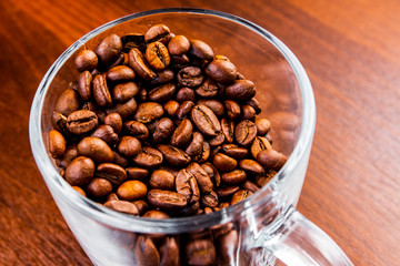 Roasted coffee beans in a glass cup isolated on a rustic dark wood table background