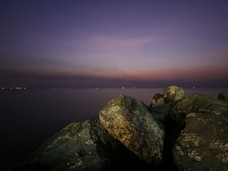 Fototapeta na wymiar Ocean water rushing by a rock on twilight time.