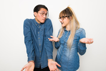 Young couple with glasses making unimportant gesture while lifting the shoulders