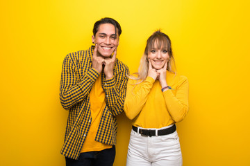 Obraz premium Young couple over vibrant yellow background smiling with a happy and pleasant expression