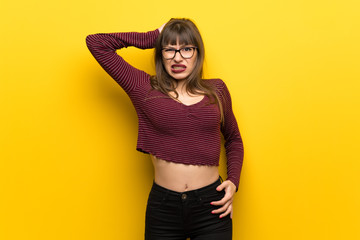Obraz premium Woman with glasses over yellow wall frustrated and takes hands on head