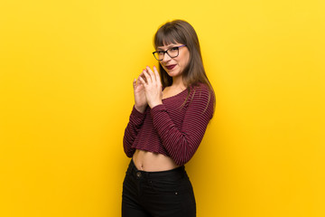 Woman with glasses over yellow wall scheming something