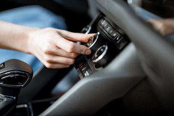 Woman turning wheel of the air conditioner in the car, close-up view