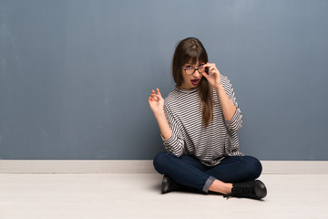 Woman with glasses sitting on the floor with glasses and surprised