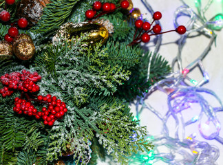 Christmas composition of pine branches, golden Christmas decorations, red berries and artificial snow.