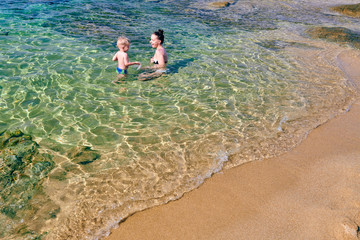 Fototapeta na wymiar Toddler boy on beach with mother