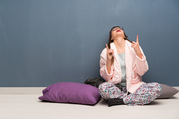 Woman in pajamas on the floor surprised and pointing up
