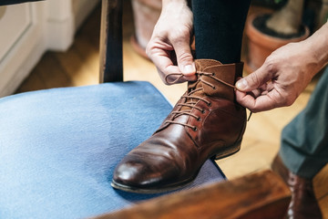 Man who attaches the laces of his brown, classy and luxurious leather shoes