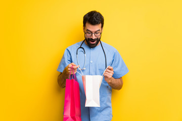 Surgeon doctor man surprised while holding a lot of shopping bags