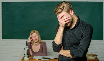 He left a lesson unlearned. University or college student covering face. Male student with examiner at examination. Handsome man standing in classroom with teacher. High school student saying lesson