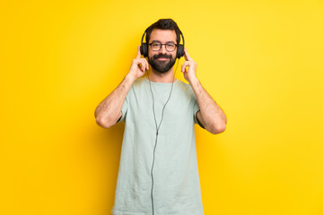 Man with beard and green shirt listening to music with headphones