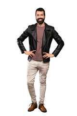 Naklejka premium Handsome man with beard posing with arms at hip and smiling over isolated white background