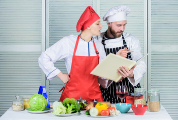 Culinary family concept. Couple in love cooking healthy recipe. Amateur cook read book recipes. Improve cooking skill. Book recipes. Helpful culinary book. Woman chef and man cooking food together