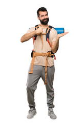 Hiker man holding copyspace imaginary on the palm to insert an ad over isolated white background