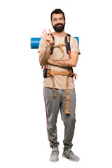 Hiker man happy and counting four with fingers over isolated white background