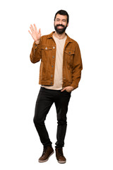 Fototapeta premium Handsome man with beard saluting with hand with happy expression over isolated white background