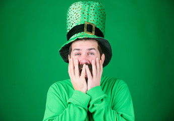 Covering his face with hands with delight. Happy Irish man with beard wearing green. Hipster in...