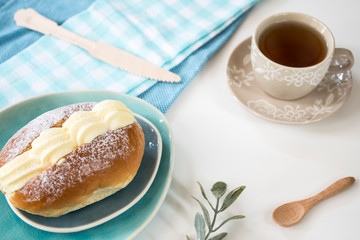 typical Dutch creamed sandwich called roombroodje or puddingbroodje on blue plate. cup of tea.
