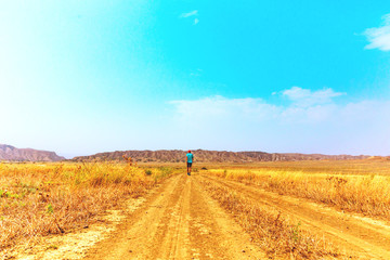 Young alone traveler guy walks wandering on hot savannah. Travel lifestyle