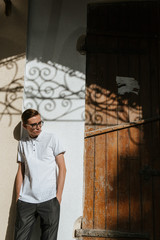 A man in white polo and gray trousers poses on the street to advertise men's clothing. Shooting for men's clothing store