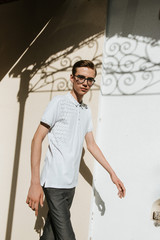 A man in white polo and gray trousers poses on the street to advertise men's clothing. Shooting for men's clothing store