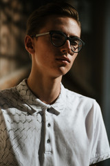 A man in white polo and gray trousers poses on the street to advertise men's clothing. Shooting for men's clothing store
